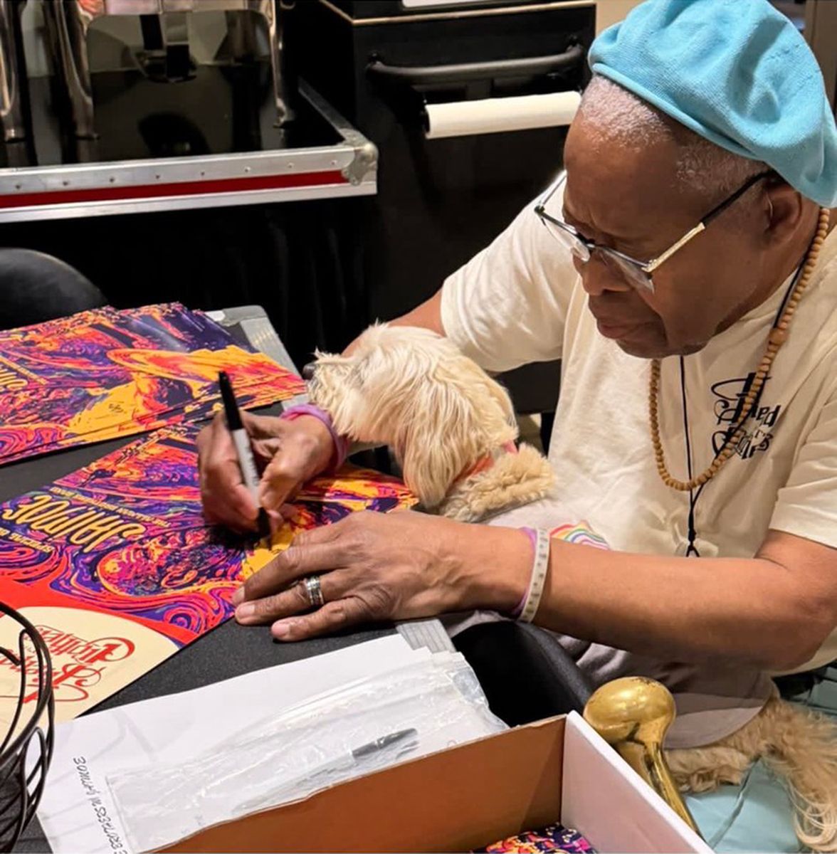 Jaimoe signing posters at the merch table